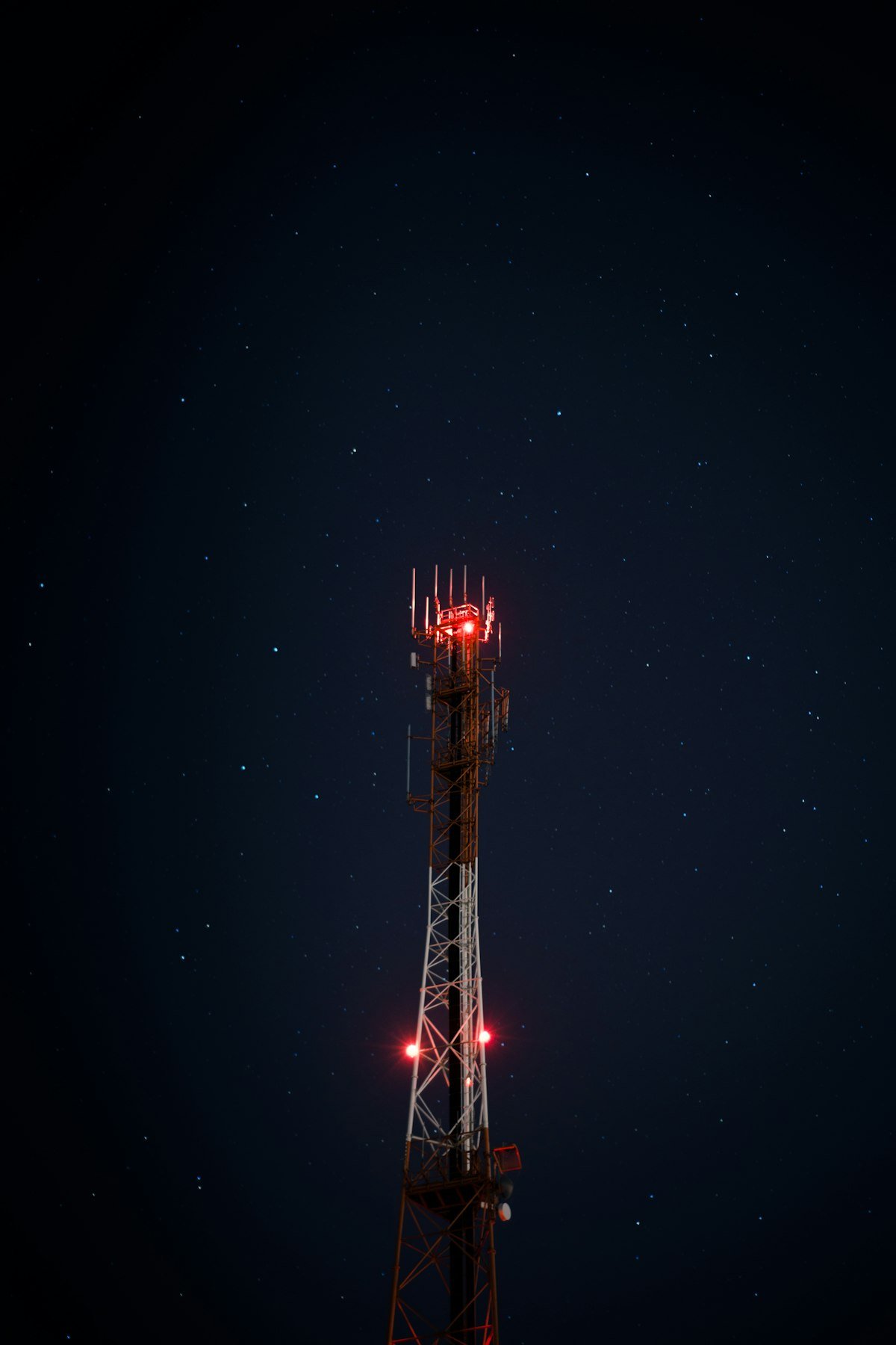 Cell tower at night with red warning lights — cellular backup in home security systems keeps your alarm connected when Wi-Fi and power fail